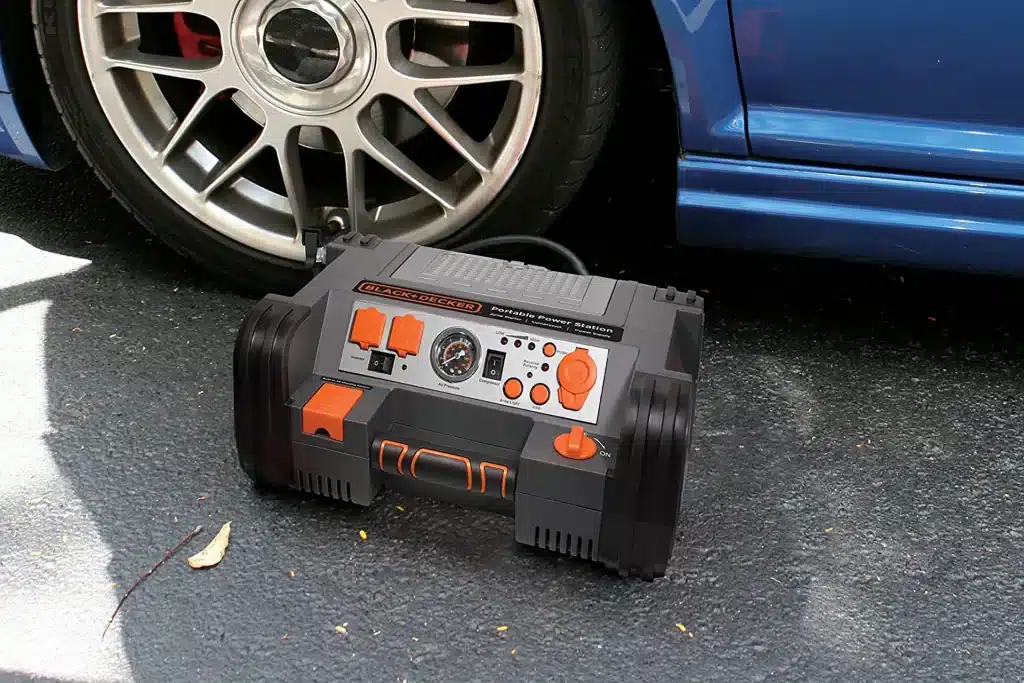 A view of a car jump starter placed next to a car wheel