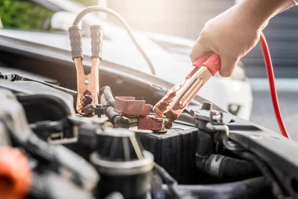 a person working with jumpers and car battery terminals