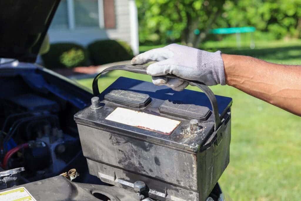 male hand wearing glove and holding a car battery