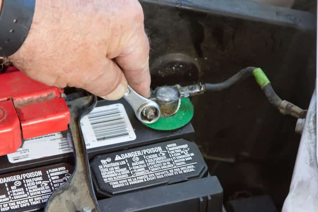 male hand wearing glove and holding a car battery