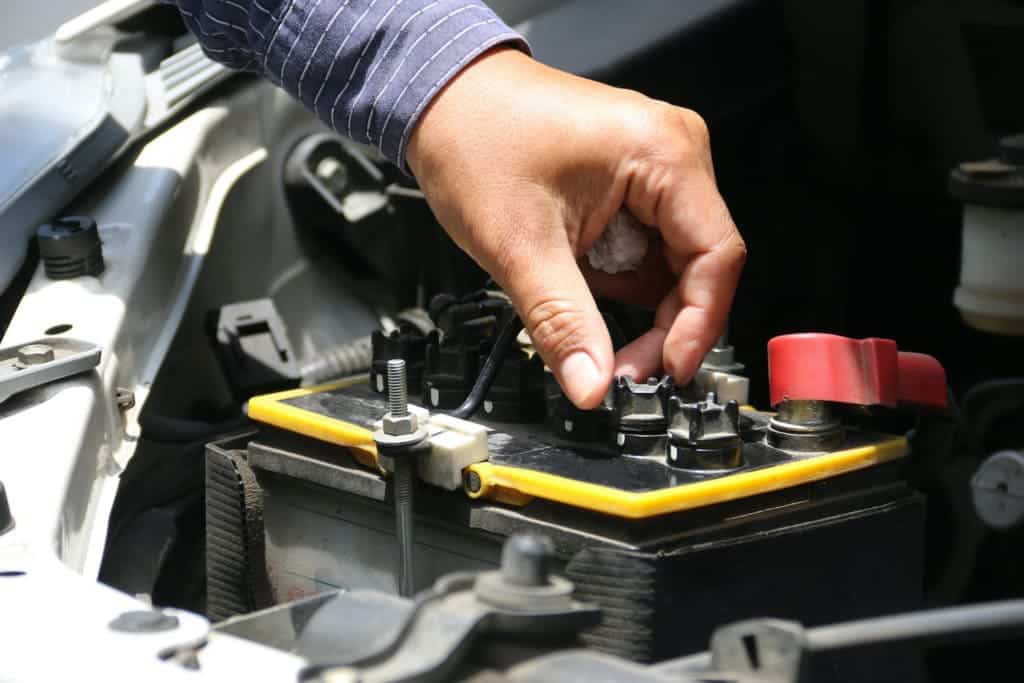 mans hand checking car battery