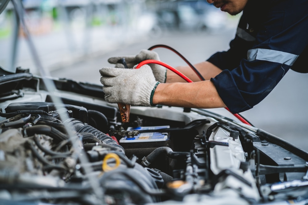 Asian Technician Measures Car Battery Voltage At Service Station Maintenance