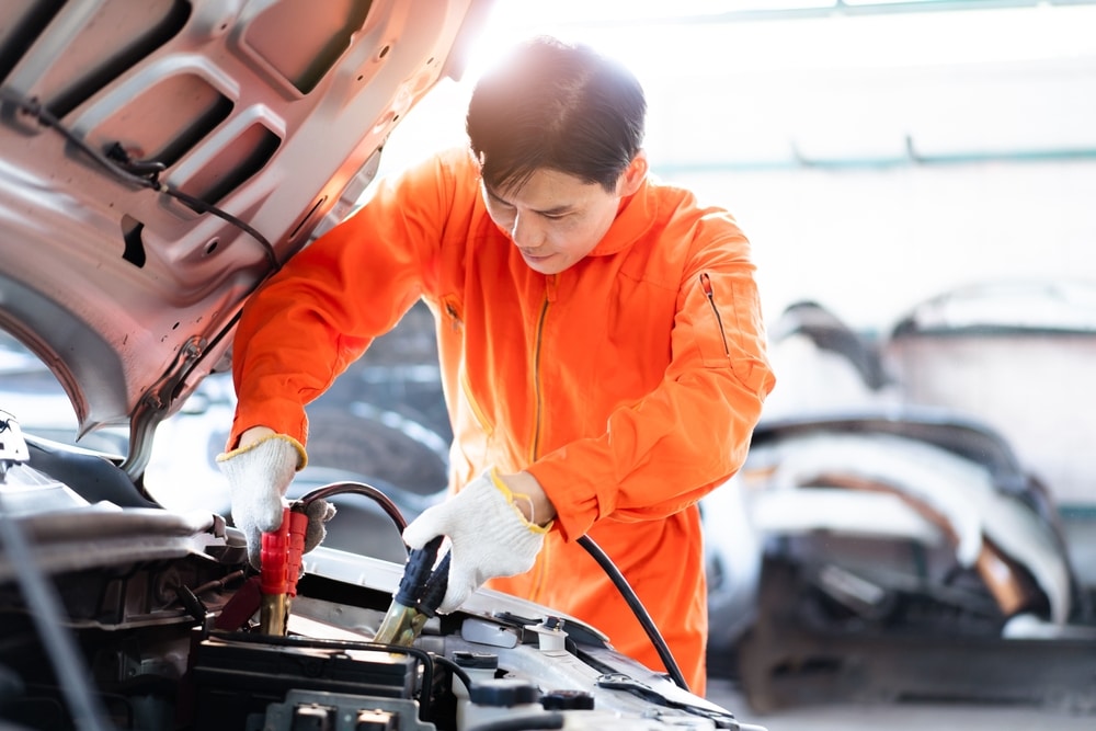 technician using an emergency jump start cable to connect a battery from other car 