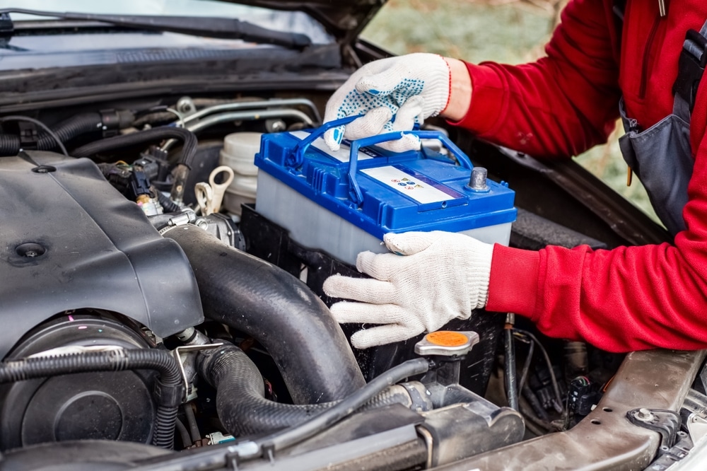 A Car Mechanic Installs A Battery In A Car Battery