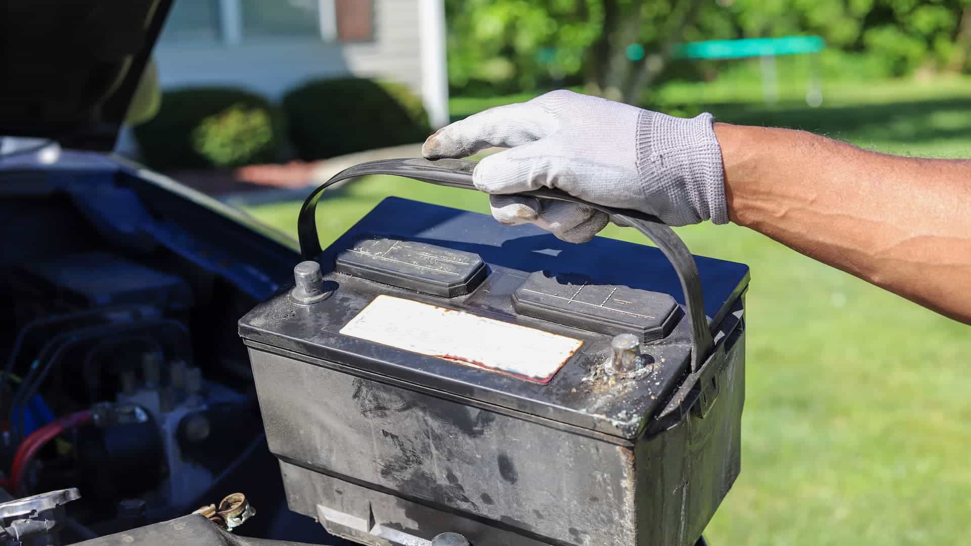 close up of a gloved hand holding a car battery