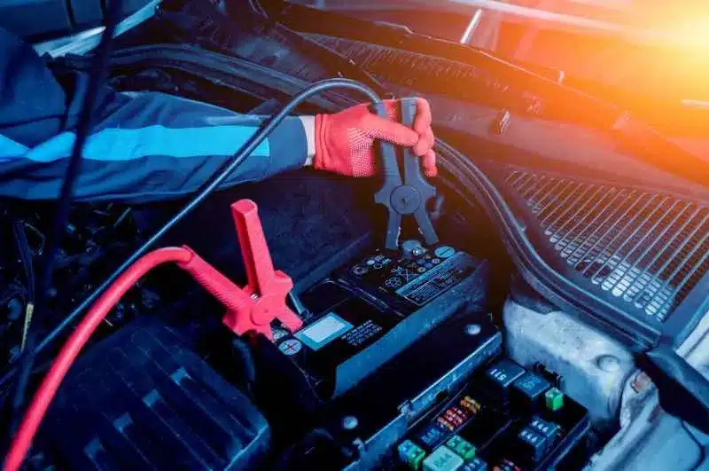 view of a hand with glove on working with negative terminal of battery