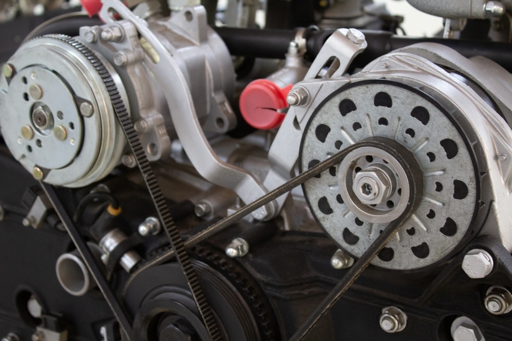 Close-up of a complex engine timing belt system, showcasing pulleys and gears on a black engine block