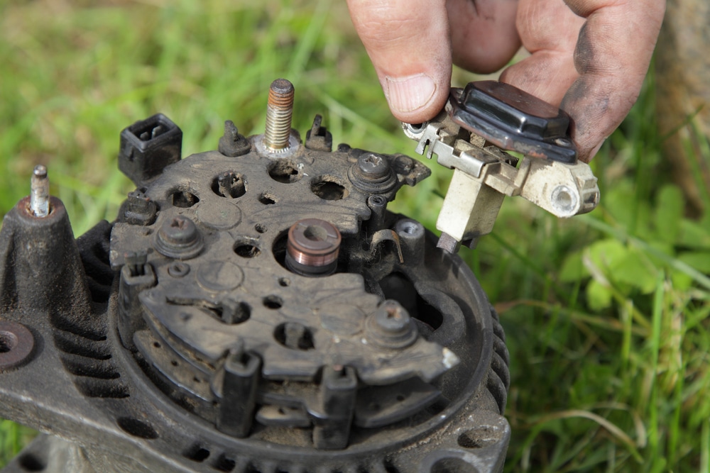 Relay voltage regulator in hands on used car 12 V alternator background close up, outdoor vehicle electric equipment repair