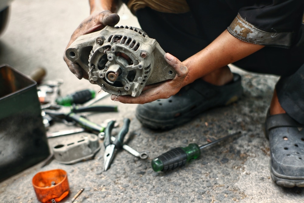  mechanic checking and repairing car alternator (dynamo)