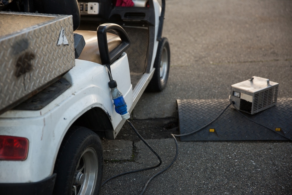 Charging Electric Vehicle From Wall Socket at Winter. charging golf cart